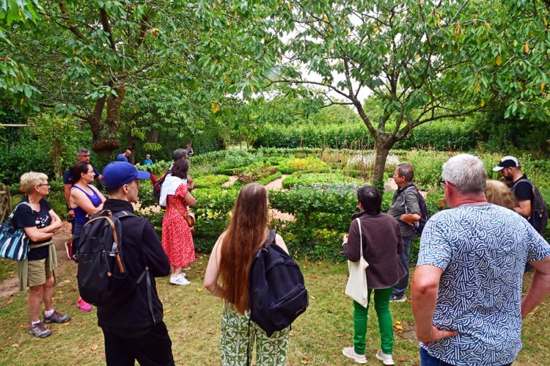 Visiteurs écoutant un guide dans les jardins médiévaux